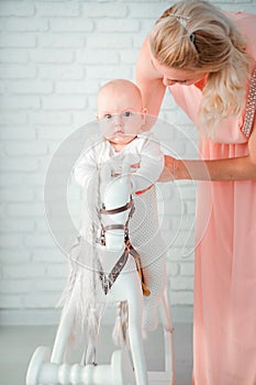 Mother rolls her little son on a toy horse