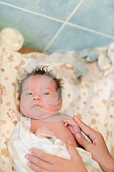 Mother rubs baby after bathing. the boy smiles and feels happy after taking a bath. mother dries and rubs the hair of the newborn