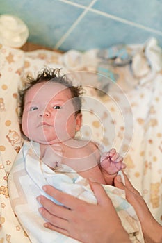 Mother rubs baby after bathing. the boy smiles and feels happy after taking a bath. mother dries and rubs the hair of the newborn