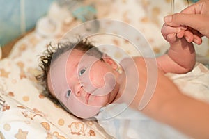 Mother rubs baby after bathing. the boy smiles and feels happy after taking a bath. mother dries and rubs the hair of the newborn