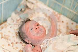 Mother rubs baby after bathing. the boy smiles and feels happy after taking a bath. mother dries and rubs the hair of the newborn