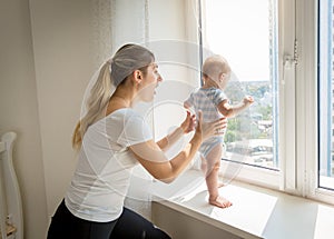 Mother rushing to her baby that is trying to open window