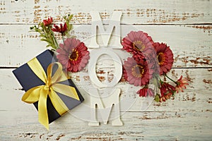 Mother`s day background with Mom alphabet letters and Flowers and gift box on wooden background
