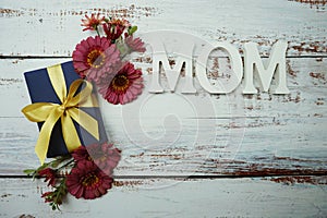 Mother`s day background with Mom alphabet letters and Flowers and gift box on wooden background