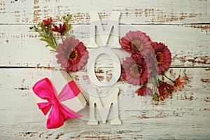 Mother`s day background with Mom alphabet letters and Flowers and gift box on wooden background