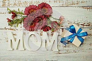 Mother`s day background with Mom alphabet letters and Flowers and gift box on wooden background