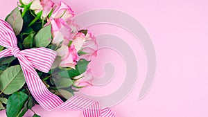 Mother`s Day background of pink roses with copy space on pink wood table.