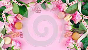 Mother`s Day background of pink roses and macaron cookies on pink wood table.
