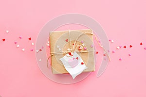 Mother's day background - red roses background with brown paper wrapped gift and heart shaped confetti on pink background.