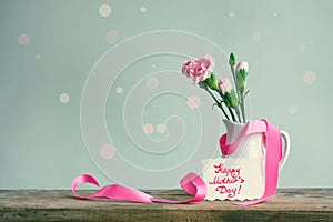 Mother`s day card, pink carnations in a white vase with ribbon