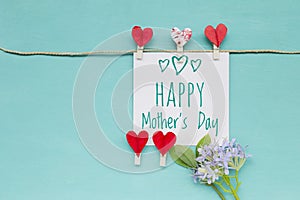 Mother\'s day card with red heart clip and flower on blue background