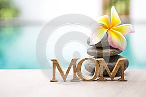 Mother`s day concept background, torpical style nature with mom wooden text over blurred swimming pool water background