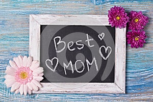 Mother`s day concept, Best Mom written on chalkboard with pink flowers on wooden background