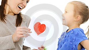 Mother& x27;s day concept. Child daughter congratulates mom and gives her postcard with red heart shape. Mum and girl happy