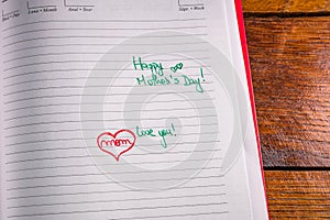 Mother`s day concept. Writing text for mother on personal agenda. Love you mom, happy mother`s day