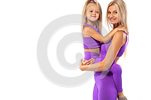 Mother`s day concept. Young mother and daughter exercise fitness together indoors. Family look.