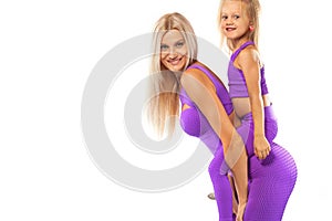 Mother`s day concept. Young mother and daughter exercise fitness together indoors. Family look.