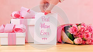 Mother`s Day gift, pink roses and Best Mom Ever greeting card on table.