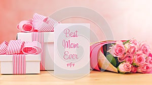 Mother`s Day gift, pink roses and Best Mom Ever greeting card on table.