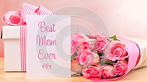 Mother`s Day gift, pink roses and Best Mom Ever greeting card on table.