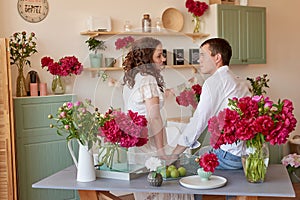 Mother`s Day Greeting Card. Happy family, pregnant woman with little daughter in kitchen with peonies flowers. Relationship