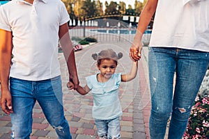 Mother`s day. Happy family spending time outdoors walking in park. Mother and her son holding little toddler girl.