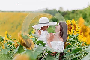 Mother`s day. Happy mother with the daughter in the field with sunflowers. mom and baby girl having fun outdoors. family concept