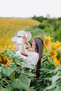 Mother`s day. Happy mother with the daughter in the field with sunflowers. mom and baby girl having fun outdoors. family concept