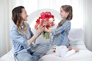 Mother`s day. Little daughter with flowers congratulates her mother