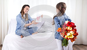 Mother`s day. Little daughter with flowers congratulates her mother