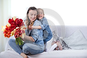 Mother`s day. Little daughter with flowers congratulates her mother