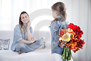 Mother`s day. Little daughter with flowers congratulates her mother