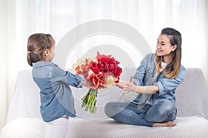 Mother`s day. Little daughter with flowers congratulates her mother