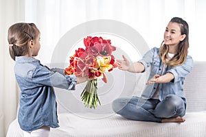 Mother`s day. Little daughter with flowers congratulates her mother