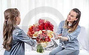 Mother`s day. Little daughter with flowers congratulates her mother