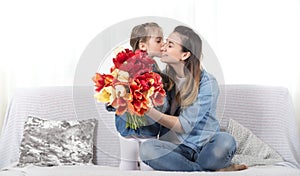 Mother`s day. Little daughter with flowers congratulates her mother