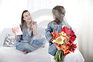 Mother`s day. Little daughter with flowers congratulates her mother