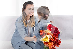 Mother`s day. Little daughter with flowers congratulates her mother