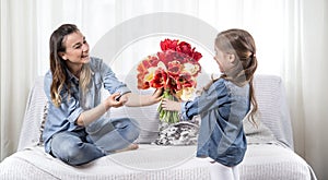 Mother`s day. Little daughter with flowers congratulates her mother