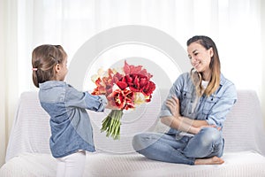 Mother`s day. Little daughter with flowers congratulates her mother