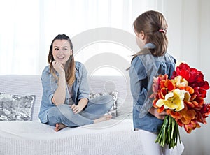 Mother`s day. Little daughter with flowers congratulates her mother