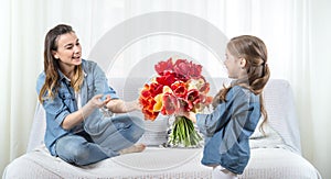 Mother`s day. Little daughter with flowers congratulates her mother