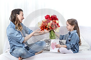 Mother`s day. Little daughter with flowers congratulates her mother