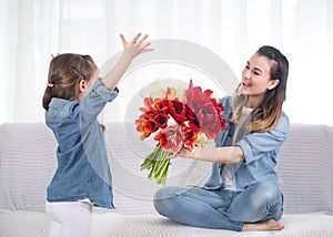 Mother`s day. Little daughter with flowers congratulates her mother