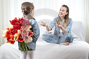 Mother`s day. Little daughter with flowers congratulates her mother