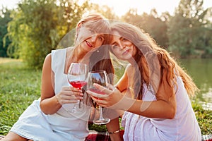 Mother`s day. Mother drinking wine with her adult daughter in spring park. Family having picnic outdoors