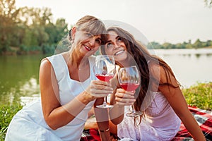 Mother`s day. Mother drinking wine with her adult daughter in spring park. Family having picnic outdoors