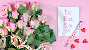 Mother`s Day overhead with roses, Best Mom Ever card and gift on pink table.