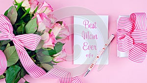 Mother`s Day overhead with roses, Best Mom Ever card and gift on pink table.