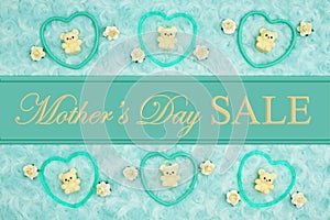 Mother`s Day Sale message with teal frame hearts, teddy bears and rose buds on a teal plush fabric